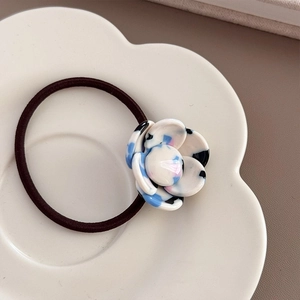 Detailed macro view of camellia resin flower elastic hair tie in a marble pattern