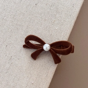 Vue détaillée d'une barrette nœud en velours marron avec perle blanche sur toile