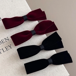 Vintage velvet bow hair clips in wine red and black on an elegant textured book background