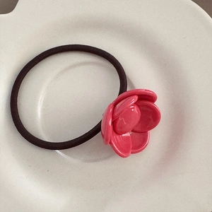 Detail view of pink resin camellia flower charm on high-elasticity braided hair tie