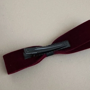Detail view of burgundy velvet bow hair clip showing the durable metal alligator grip