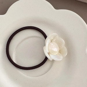 Detailed macro of cream white camellia hair tie with high-elastic dark brown woven rope