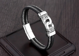 Detalle de pulsera de cuero trenzado negro con cierre magnético de acero inoxidable grabado