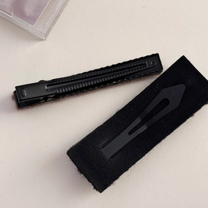 Dettaglio di fermagli per capelli neri rettangolari in metallo e lana di agnello