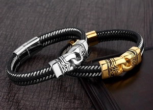 Detalle de pulseras de cuero trenzado negro con hebillas de metal tallado en oro y plata
