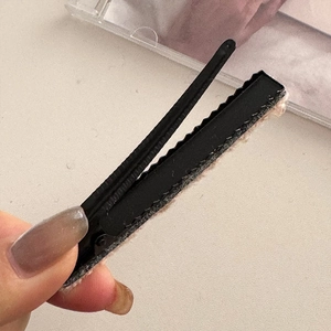 Dettaglio della clip per capelli nera opaca con fodera interna in lana d'agnello