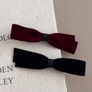 French vintage velvet bow hair clips in wine red and black on a textured book