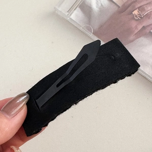 Dettaglio del fermaglio per capelli in lana nera con clip BB in metallo sul retro