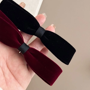 Detailed view of velvet bow hair clips in black and burgundy colors with ribbon detail