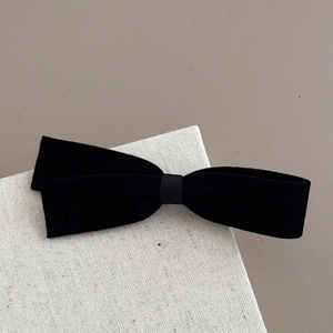 Detail of premium black velvet bow hair clip showing soft fabric texture and elegant finish