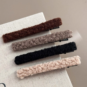 Dettaglio di quattro fermagli per capelli in lana d'agnello in marrone, grigio, nero e beige