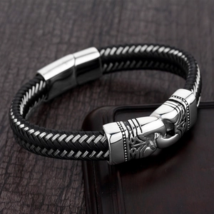 Pulsera trenzada de cuero para hombre con cierre de gancho plateado en fondo de madera