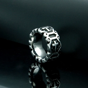 Close-up of vintage steel ring featuring embossed cross symbols and geometric textures