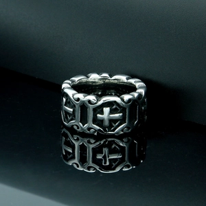 Vintage stainless steel cross ring with intricate floral carvings on reflective background