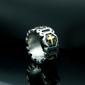 Vintage Gothic cross ring with silver and gold tones on a sleek reflective surface