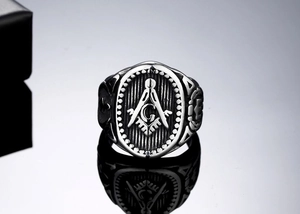 Macro shot of Freemason Masonic symbol ring with Square and Compasses on black surface