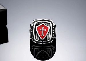 Close-up of medieval shield ring with red enamel background and white cross design
