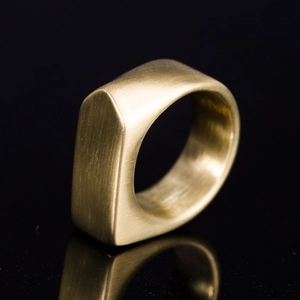Makroaufnahme eines industriellen Gold-Titanstahlrings mit gebürsteter Metallstruktur und Kanten