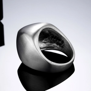 Anello minimalista in acciaio inossidabile argento opaco su una superficie nera lucida
