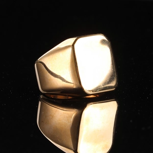 Polished minimalist gold stainless steel signet ring for men on a black reflective background