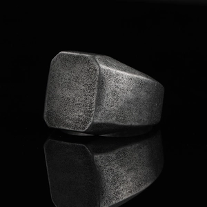 Macro detail of industrial square signet ring with vintage matte grainy texture on black mirror