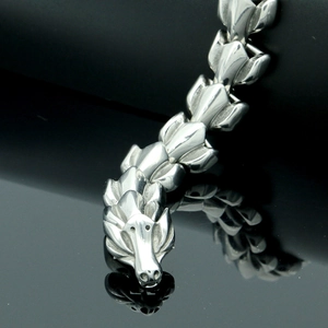 Macro detail of silver dragon head clasp and interlocking scales on steel biker bracelet