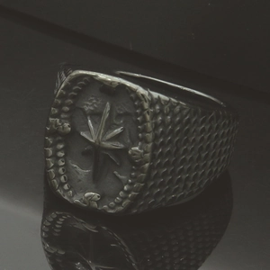 Macro detail of men's vintage compass signet ring with scale texture and matte finish