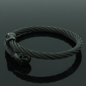 Vista macro de pulsera de cable de acero negro trenzado con calaveras góticas