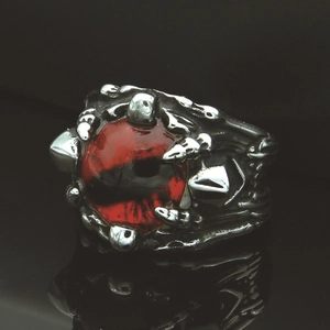 Dettaglio macro dell'anello con artiglio di drago gotico e occhio di vetro rosso intenso