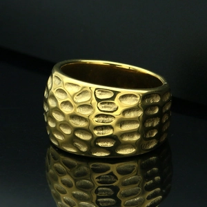 Detail shot of golden titanium steel ring with textured hammered surface on black background