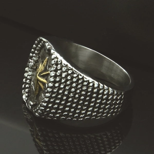 Detail shot of vintage silver ring with golden compass motif on textured surface