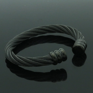 Detalle de brazalete de cable trenzado negro mate sobre superficie reflectante