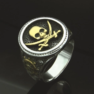 Macro shot of silver and gold skull pirate ring with embossed ship wheel detail