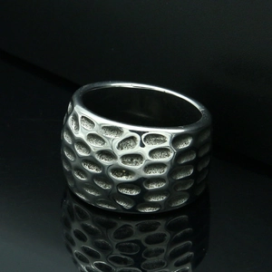 Macro shot of wide band stainless steel ring with polished honeycomb hammer texture