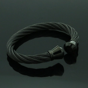Detalle de pulsera de cable de acero negro trenzado con terminales lisos redondeados