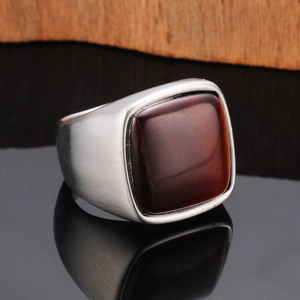 Detail of vintage men's steel ring featuring red tiger eye stone and brushed texture