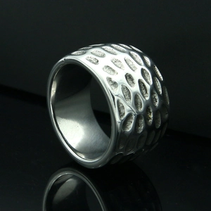 Macro shot of polished silver stainless steel ring with deep oval groove texture and reflection