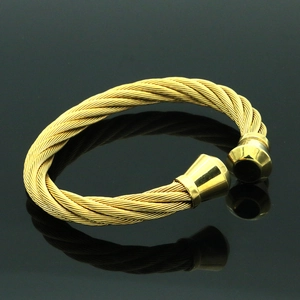 Primer plano de pulsera de cable trenzado dorado con puntas cónicas pulidas y brillo