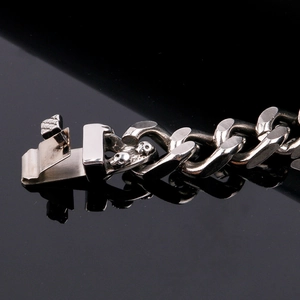 Close-up of vintage silver skull clasp with woven texture on punk cuban link bracelet