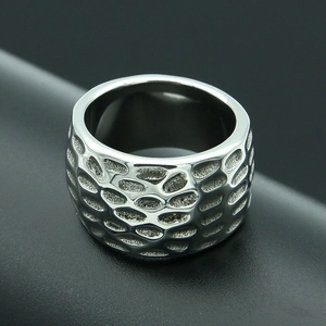 Macro detail of men's wide stainless steel ring with industrial honeycomb texture