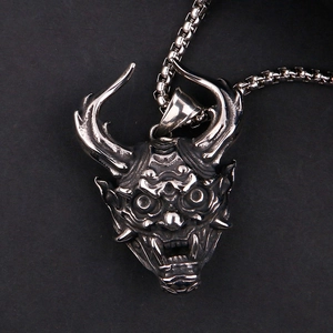 Macro detail of vintage silver Hannya mask pendant on a box chain with gothic punk style