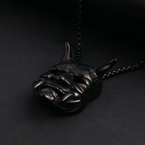 Macro detail of gothic hannya skull mask pendant in antique silver finish on black background