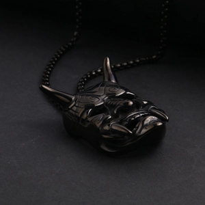 Detailed close-up of a matte black punk Hannya skull pendant with dark beaded chain