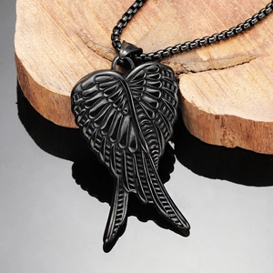 Close-up of black gothic wing pendant with detailed feather carving on natural wood