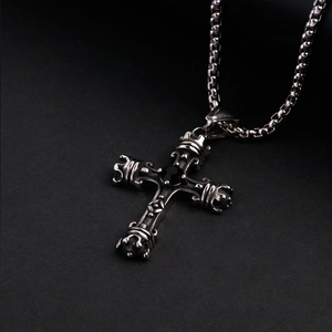 Gros plan du pendentif croix vintage en acier inoxydable avec pierre noire et détails couronne