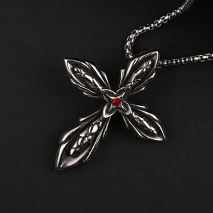 Dettaglio macro del ciondolo a croce in argento vintage con un rubino rosso centrale