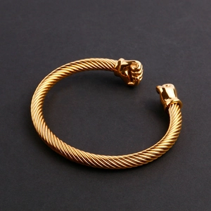 Gros plan du bracelet torsadé doré avec motifs de poing détaillés en acier inoxydable