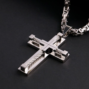 Close-up of silver stainless steel cross pendant with detailed metal wire weaving