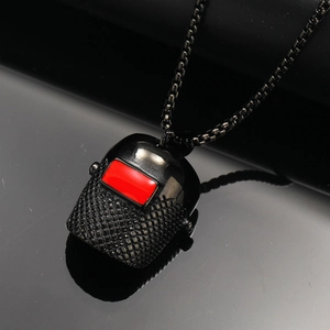 Macro view of black steel welding mask pendant with red enamel window and mesh texture