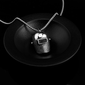 Macro detail of industrial titanium steel welding helmet pendant on black display tray